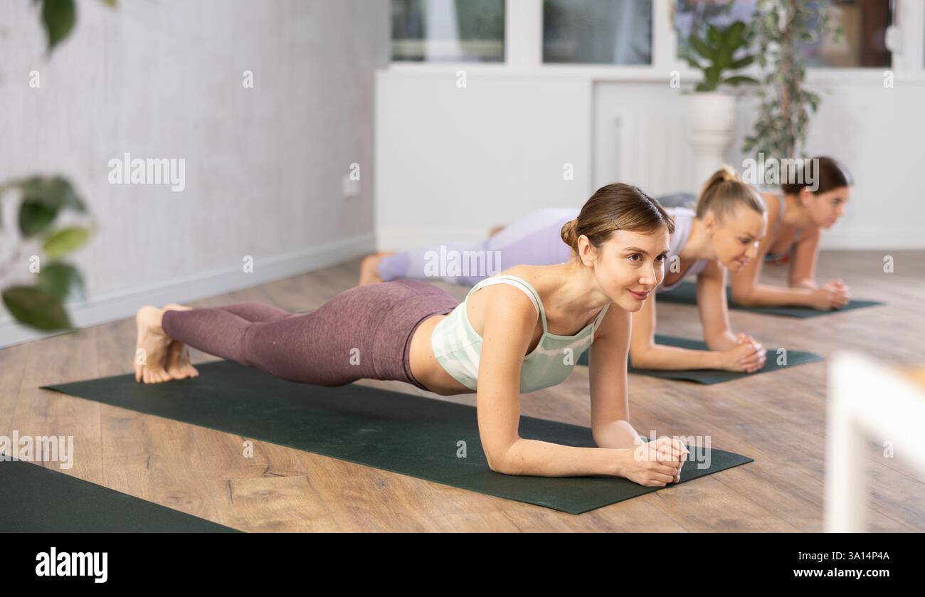 Young woman practicing plank pose in yoga studio Stock Photo