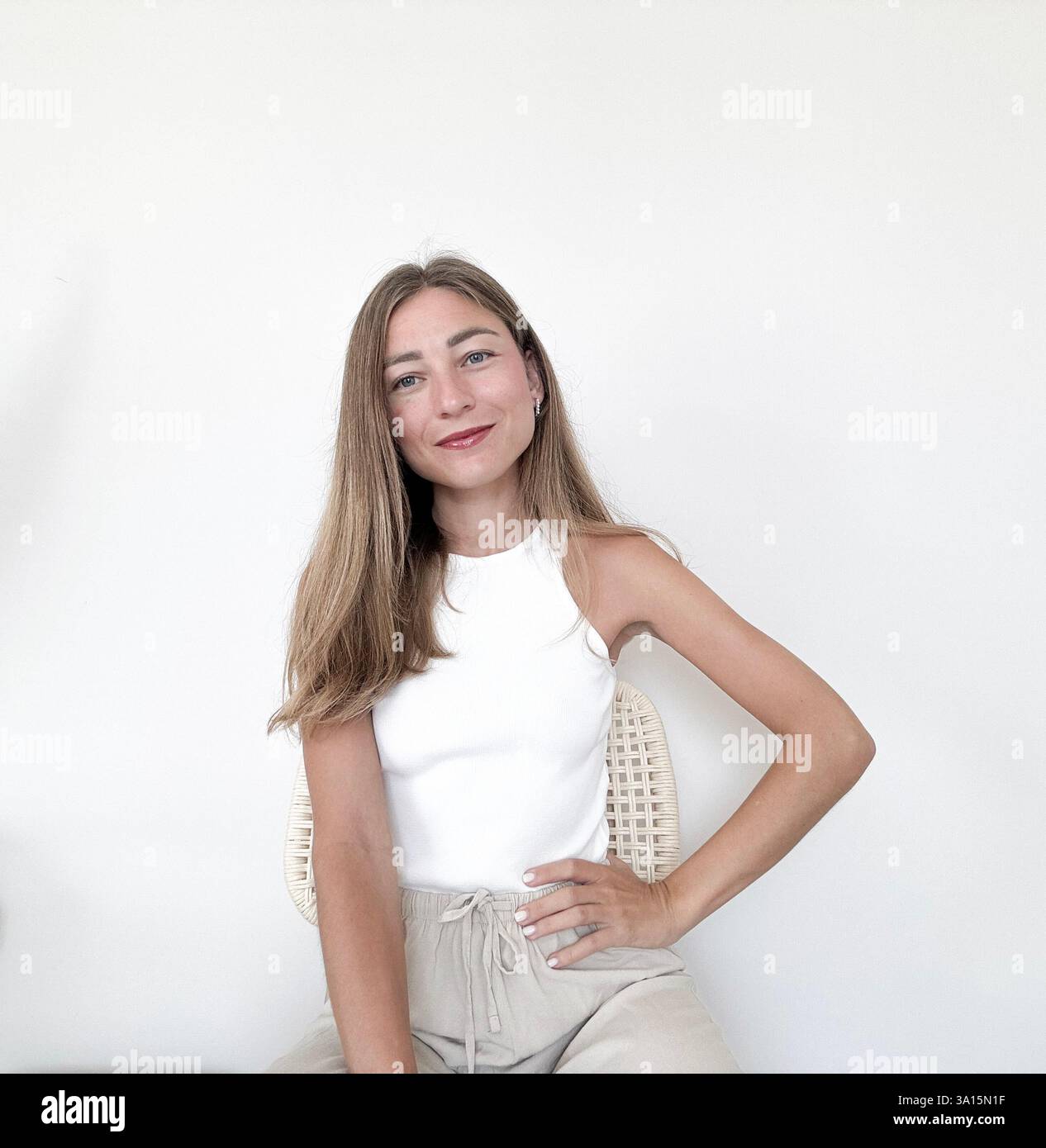 Young woman poses confidently in casual clothing against a neutral background Stock Photo