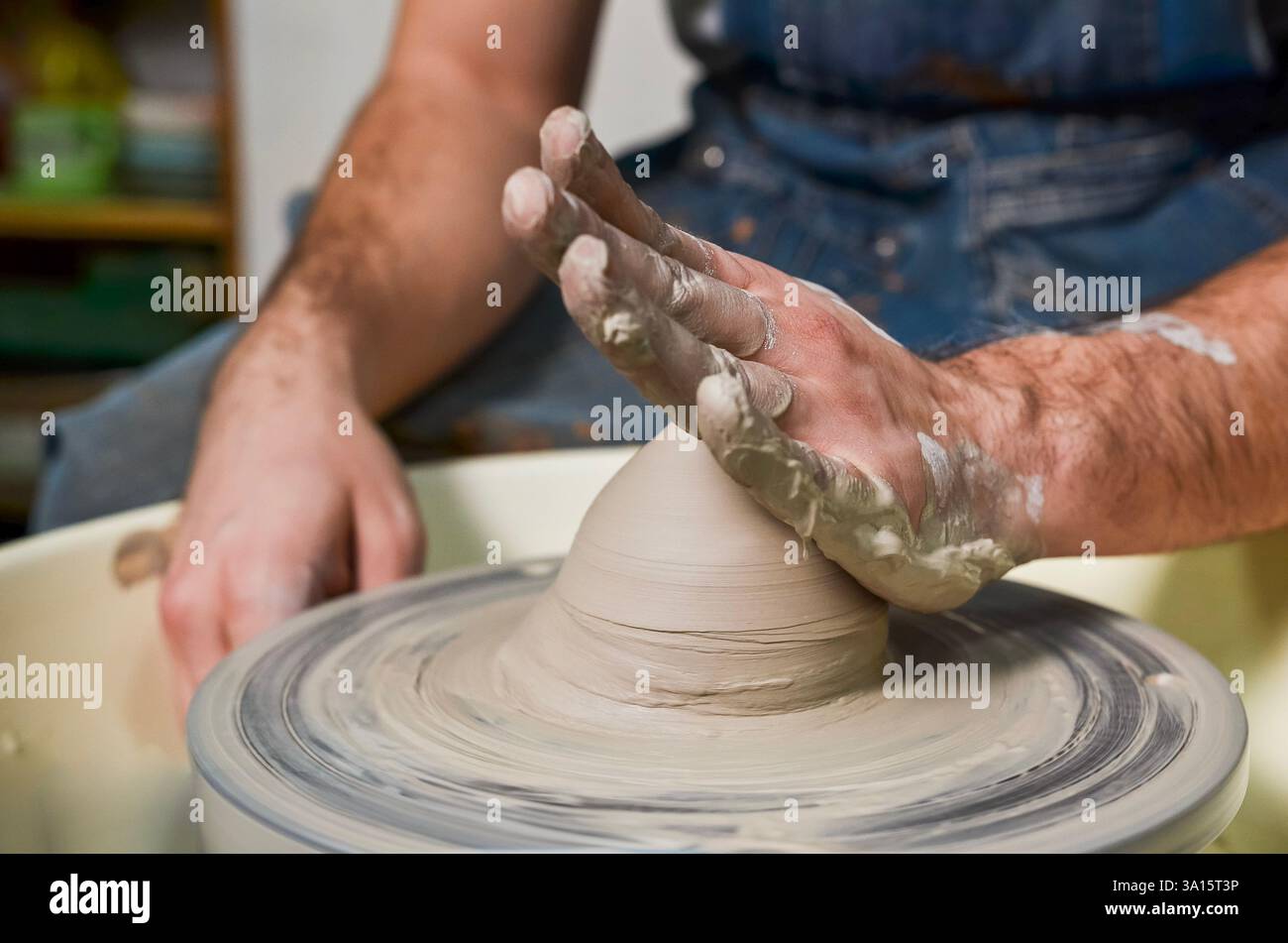 Potter modeling clay on pottery wheel, shaping pot in workshop Stock Photo