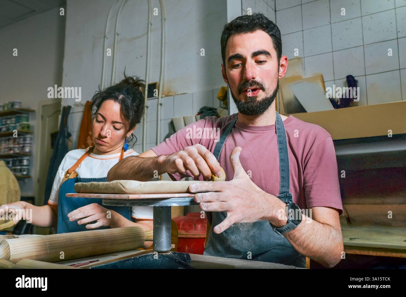 Potter explaining clay work to his female apprentice in a pottery workshop Stock Photo