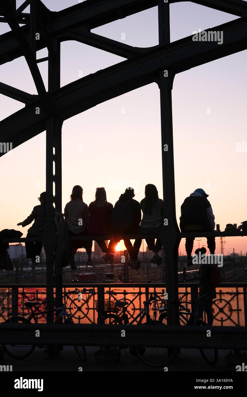 Personen sitzen auf Hackerbrücke und genießen Abendsonne Personen sitzen auf der Hackerbrücke und genießen die Abendsonne. Das historische Wahrzeichen Stock Photo