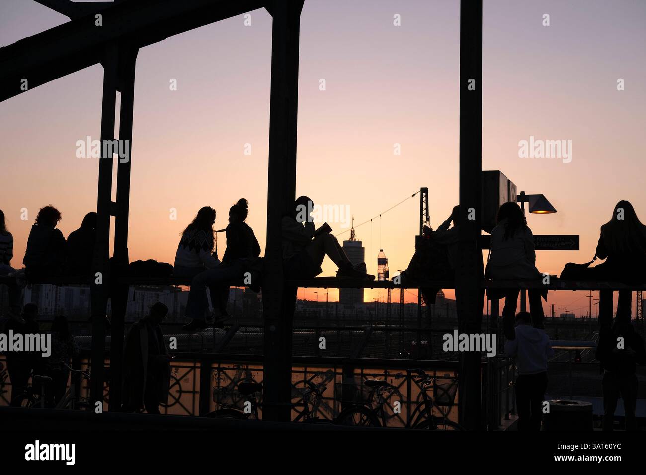 Personen sitzen auf Hackerbrücke und genießen Abendsonne Personen sitzen auf der Hackerbrücke und genießen die Abendsonne. Das historische Wahrzeichen Stock Photo