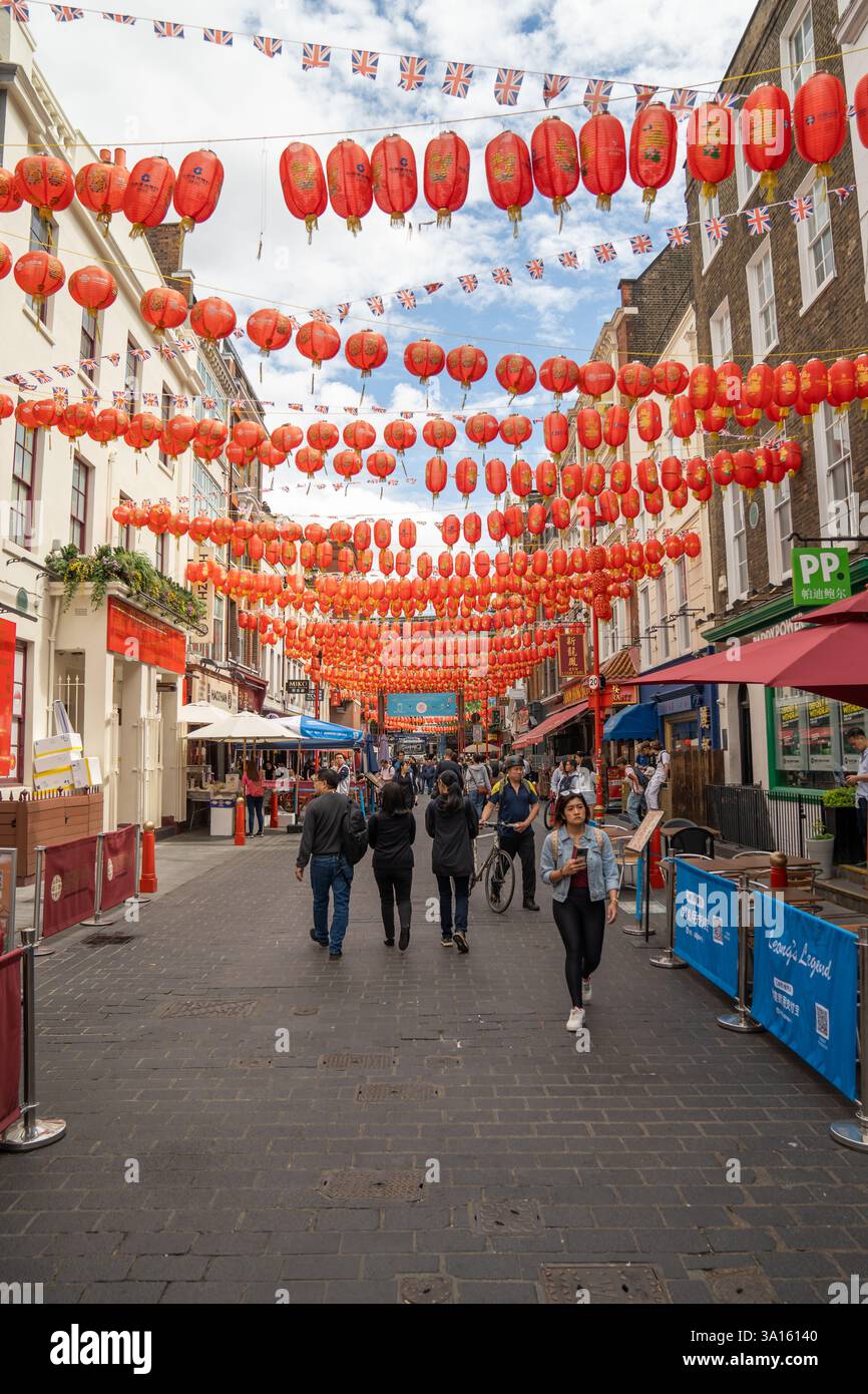 London, England, 11 July 2023, A Bustling Street in Chinatown Adorned with Red Lanterns Showcases the Vibrant Cultural Scene Amidst Restaurants and Ma Stock Photo