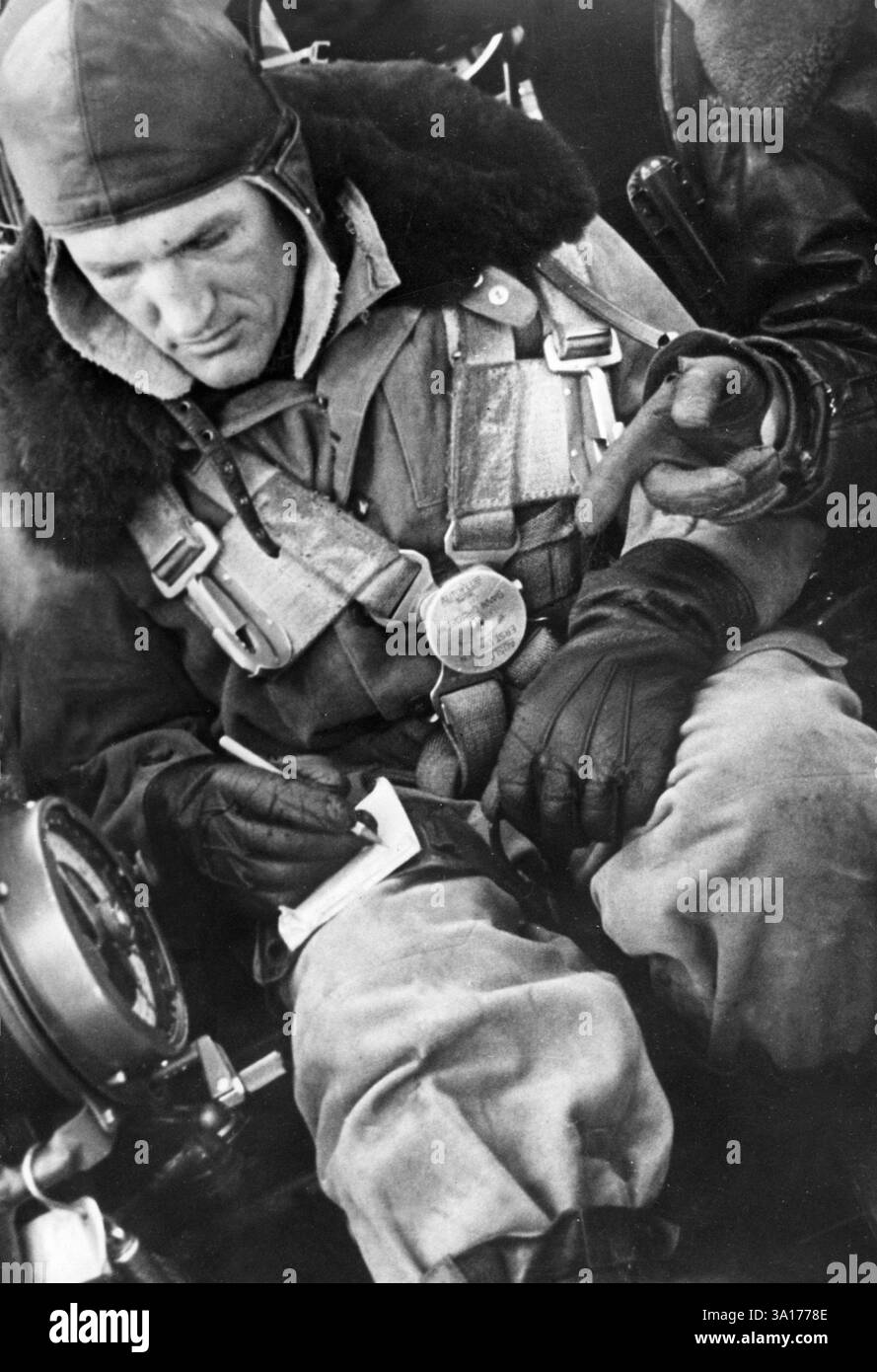 The observer of an He 111 notes down a message for the radio operator ...