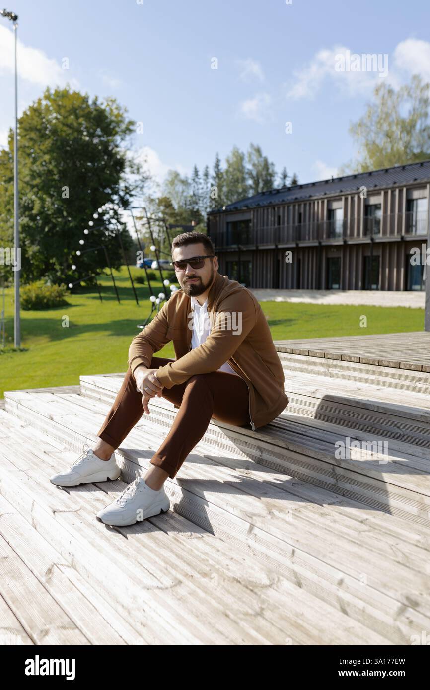 Handsome young adult man sitting on outside terrace stairs Stock Photo ...