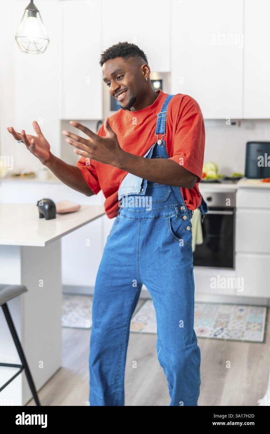 Happy young black man dancing urban style in modern kitchen, enjoying music and expressing positive emotions Stock Photo