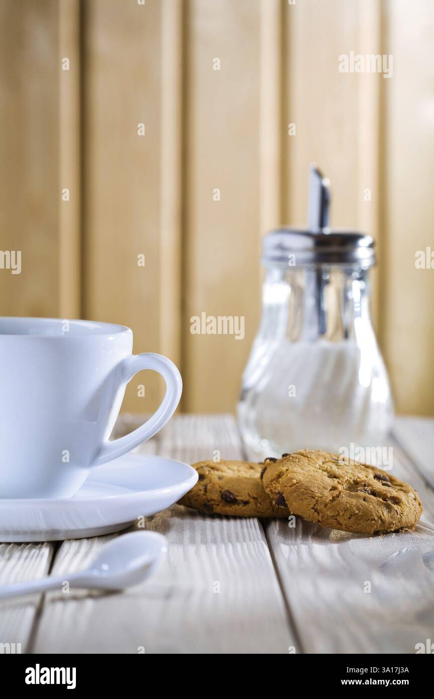 Cup with cookies and sugar dispenser on table Stock Photo