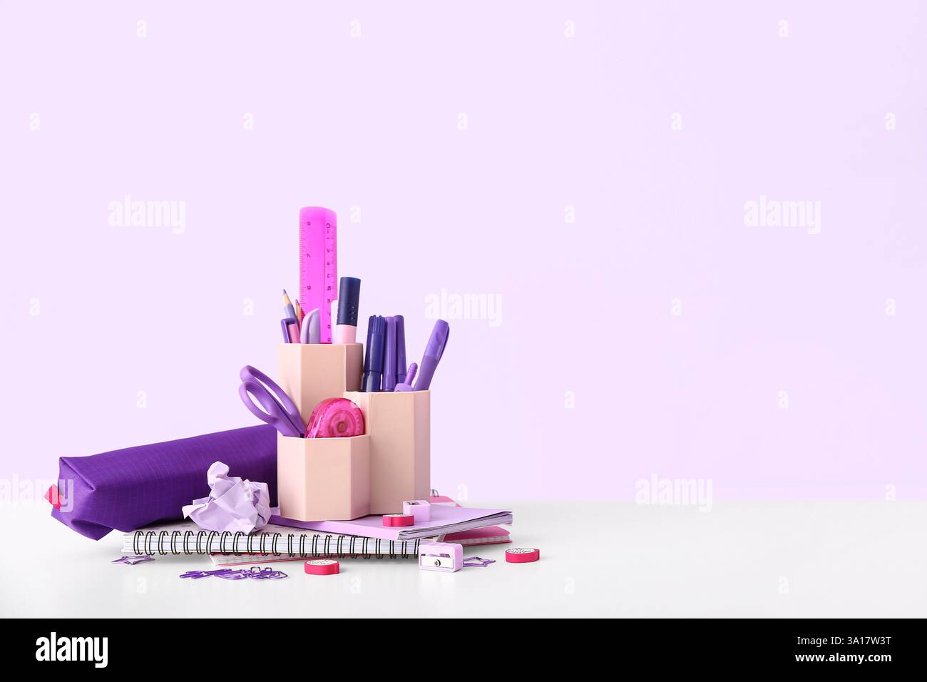 Holder with different stationery and notebooks on light desk Stock Photo