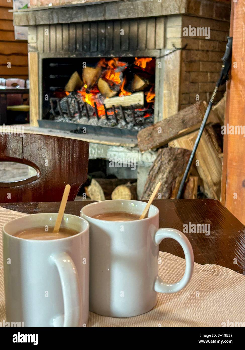 A cozy moment by the fireplace with a warm cup of hot chocolate. The flickering flames create a comforting ambiance, perfect for relaxation. - Smartphone Captured Stock Image