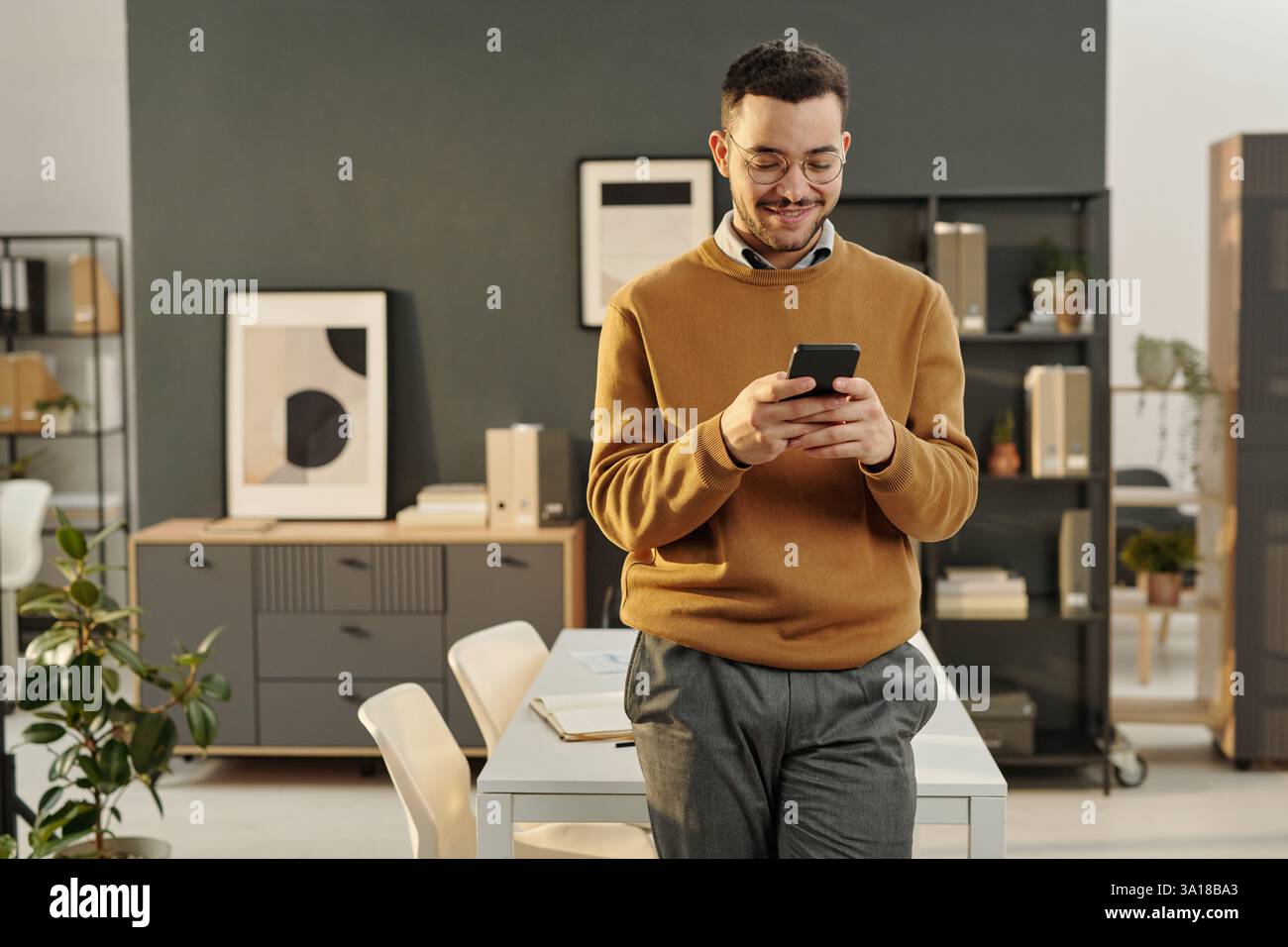 Young Man Using Smartphone in Office Stock Photo
