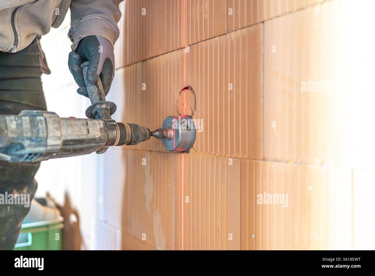 Construction worker using core drill and laser level on brick wall Stock Photo