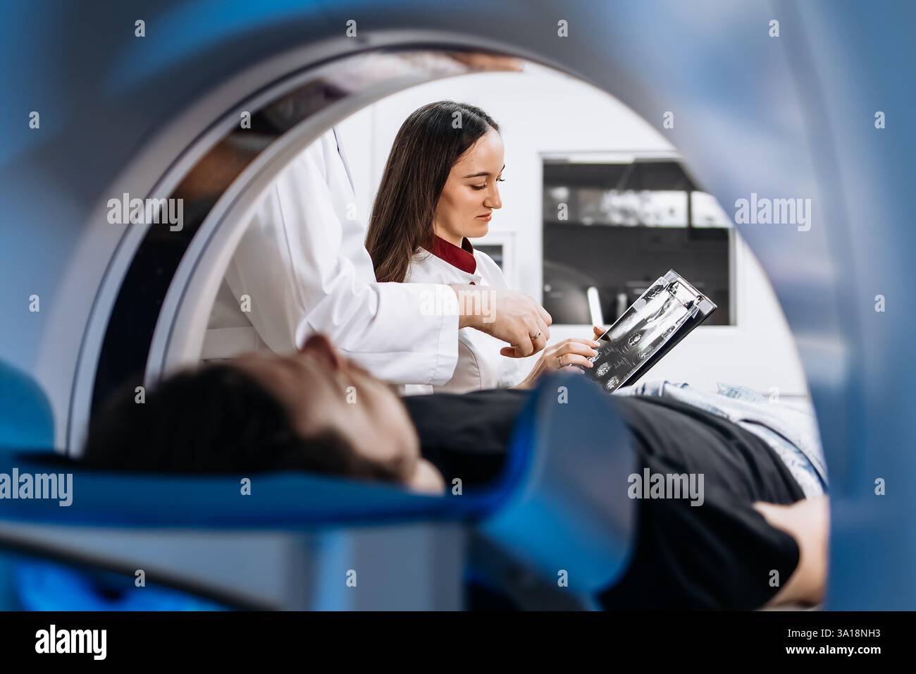The patient lies inside an MRI or CT machine where the scan is ...