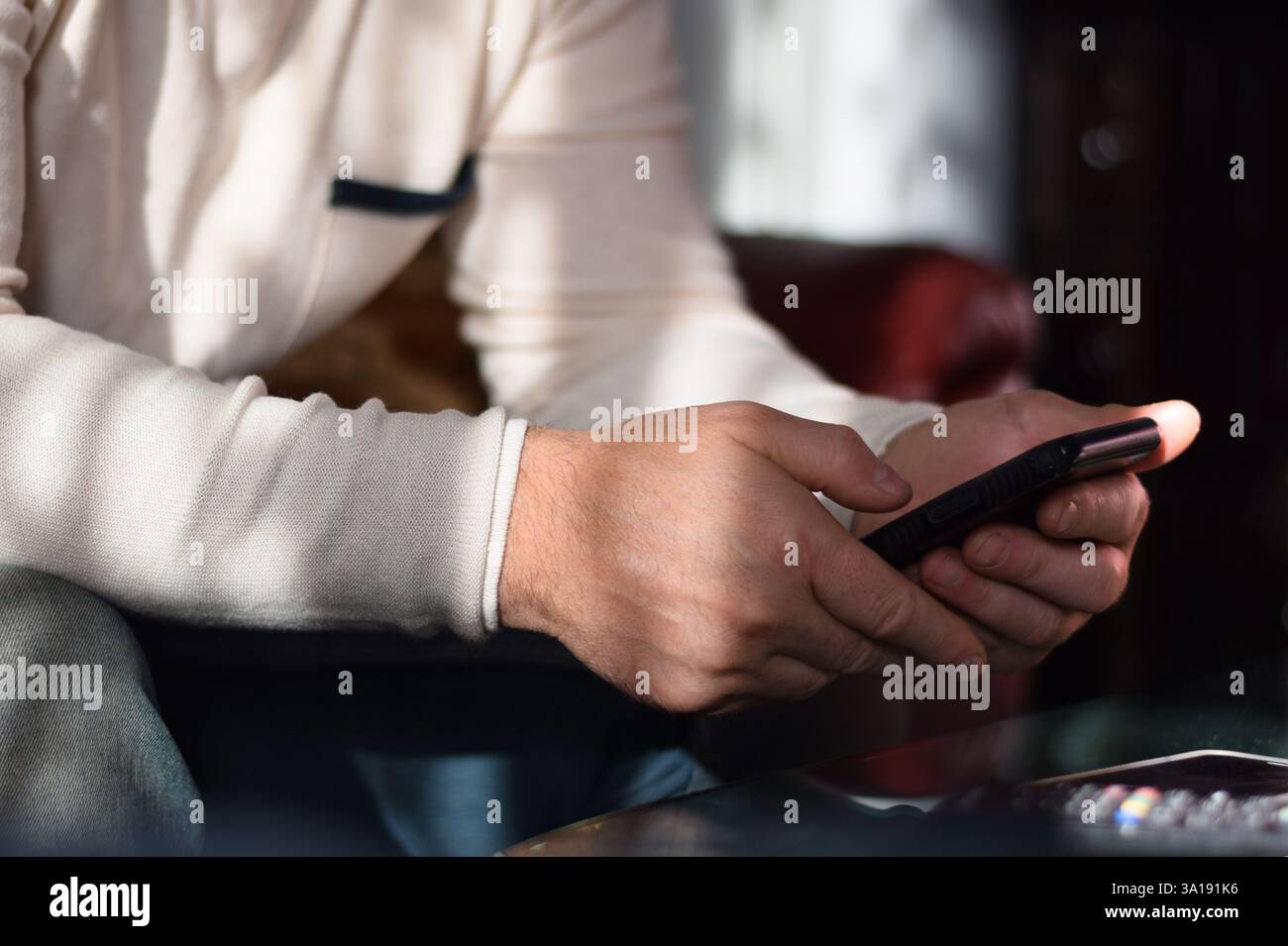 Man is sitting on a couch using mobile phone Stock Photo
