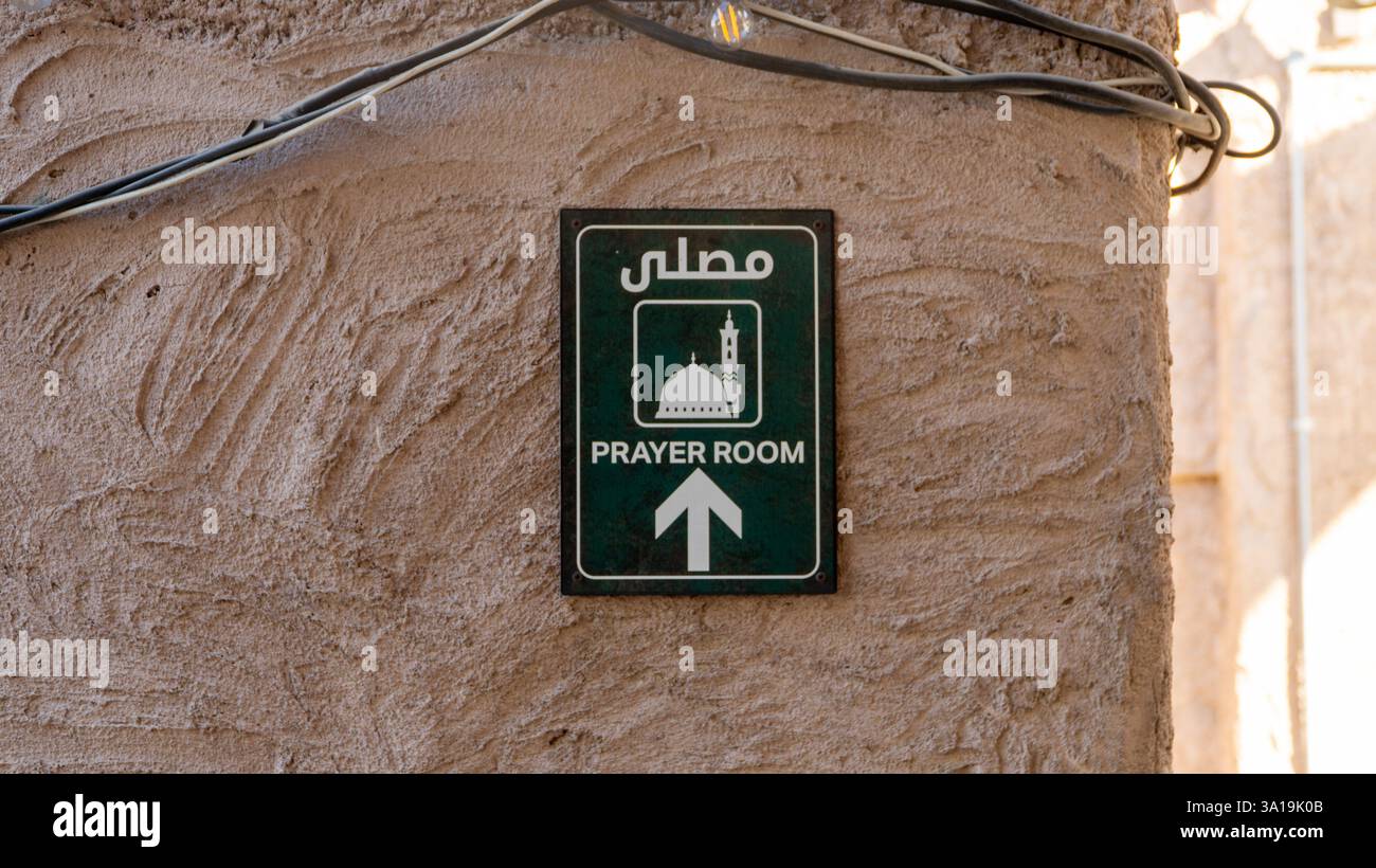 A sign pointing to the direction of a prayer room on a wall at Al Seef district, Dubai, United Arab Emirates Stock Photo