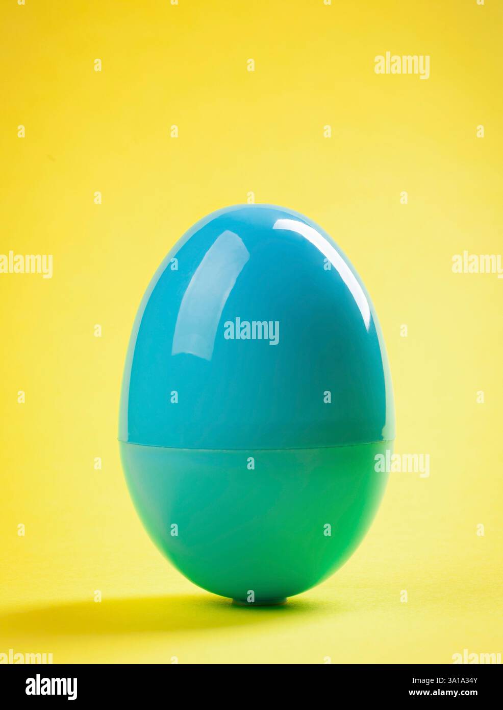 Blue plastic egg close up on yellow background. Stock Photo