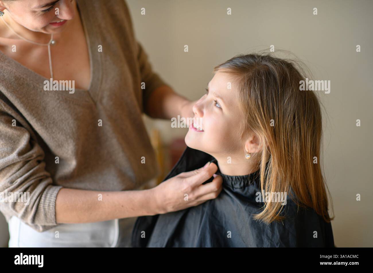 A cape is being fastened around the girl in preparation for a haircut ...
