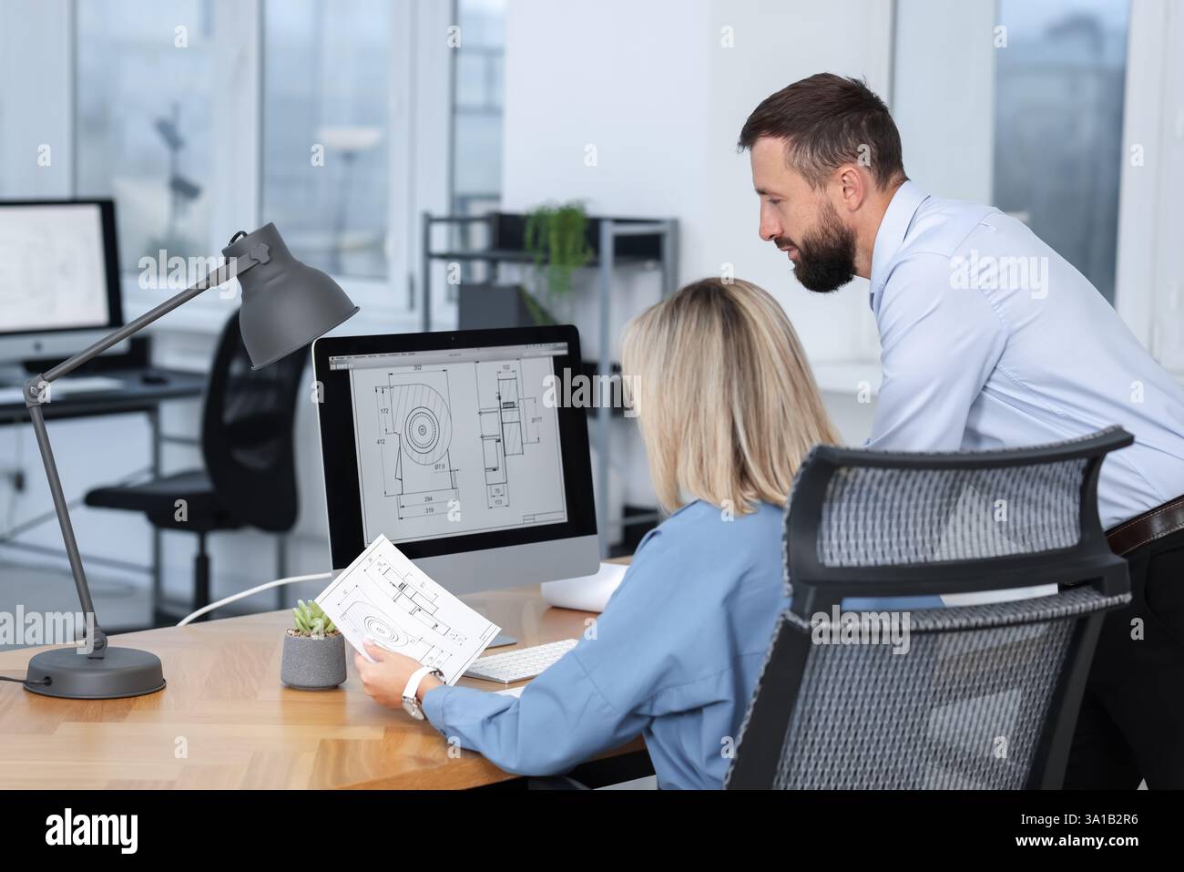 Technicians making digital engineering drawing on computer at desk in office Stock Photo