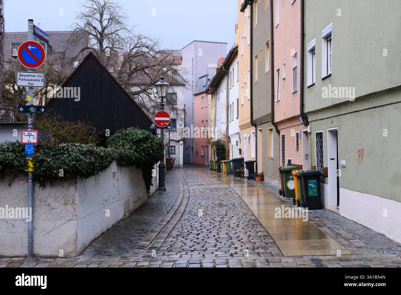 Houses in Schlossermauer Gasse in Augsburg's old town. The ground is a little wet, garbage cans are lined up neatly in front of the houses ready to be emptied. Stock Photo