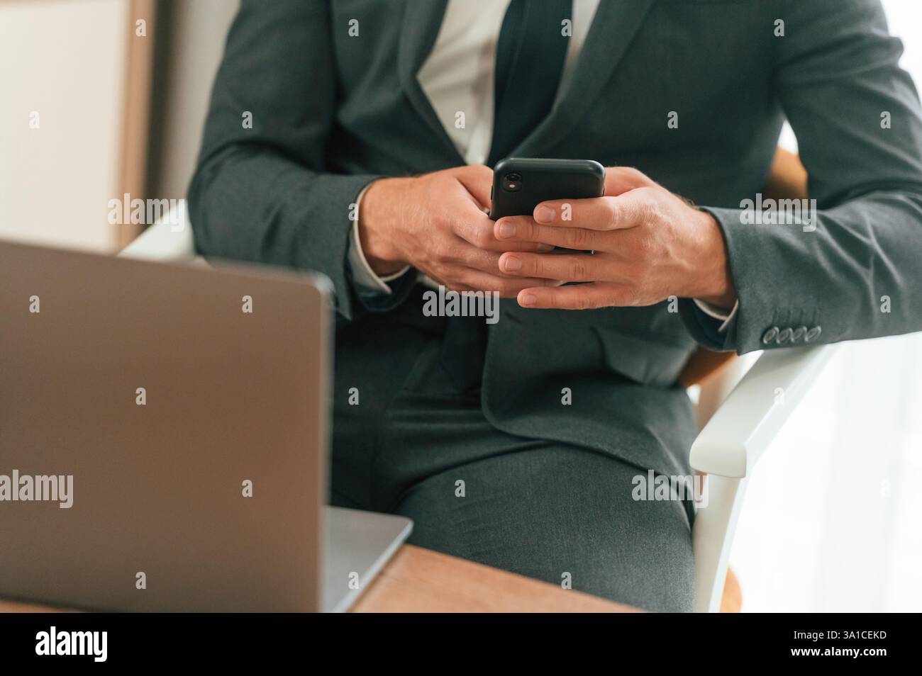 Close up view of businessman that is sitting and using smartphone. Stock Photo