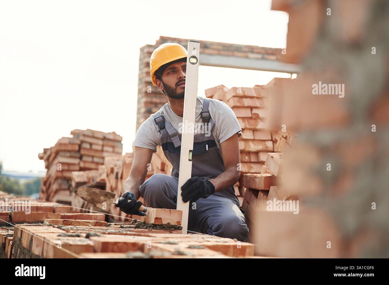 Using the leveler. Handsome Indian man is on the construction site. Stock Photo