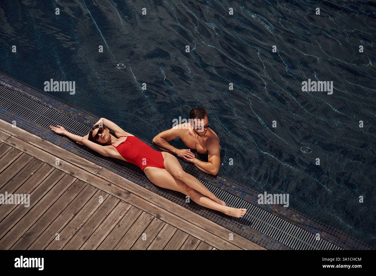 Woman is lying down. Man is in the pool. Stock Photo