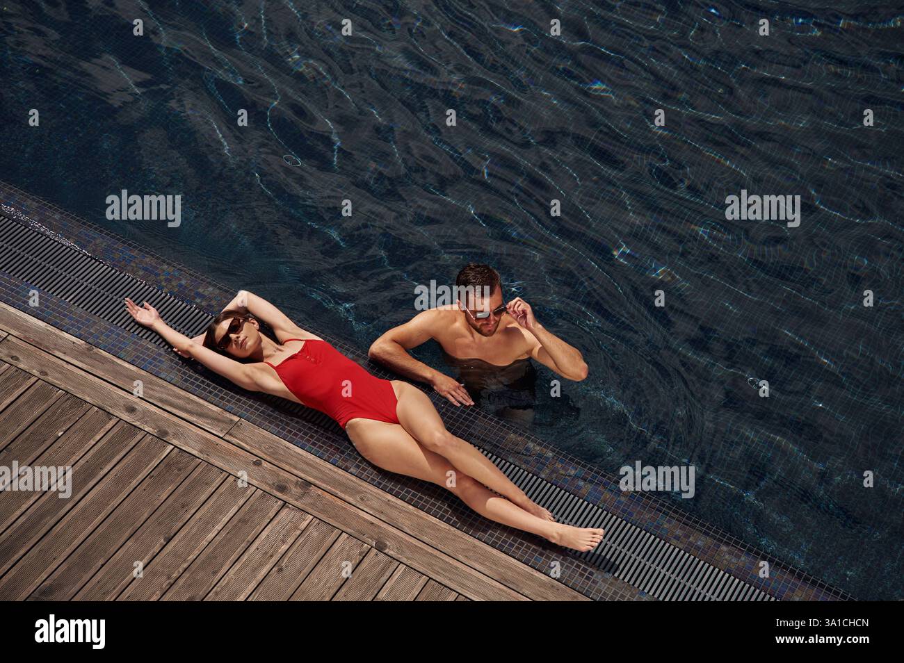 Woman is lying down. Man is in the pool. Stock Photo