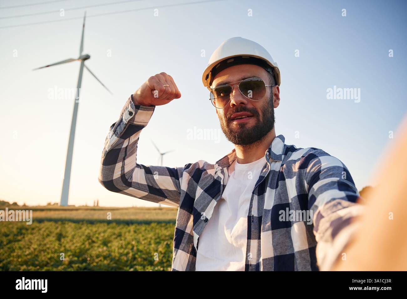 Making selfie. Service engineer is on the field with windmills. Stock Photo