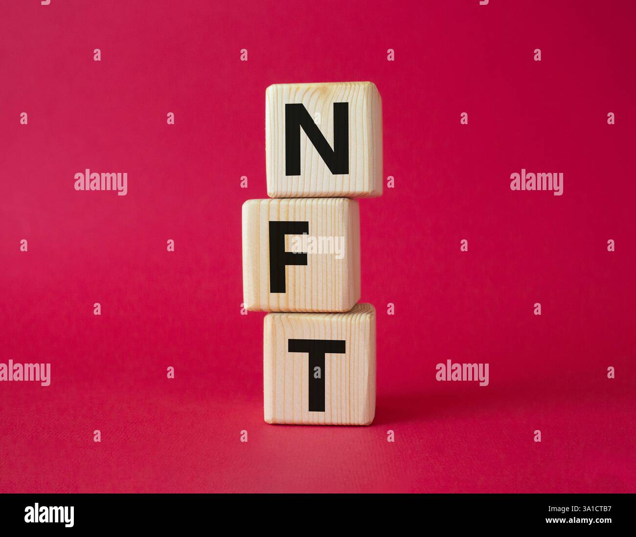 NFT - non-fungible token symbol. Concept word NFT on wooden cubes. Beautiful red background. Business and NFT concept. Copy space. Stock Photo