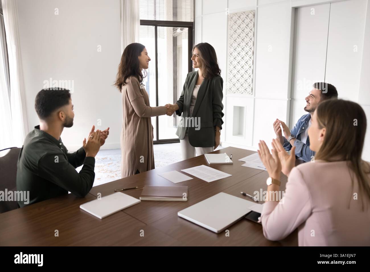 Boss welcoming staff member, handshaking to applauses of meeting ...