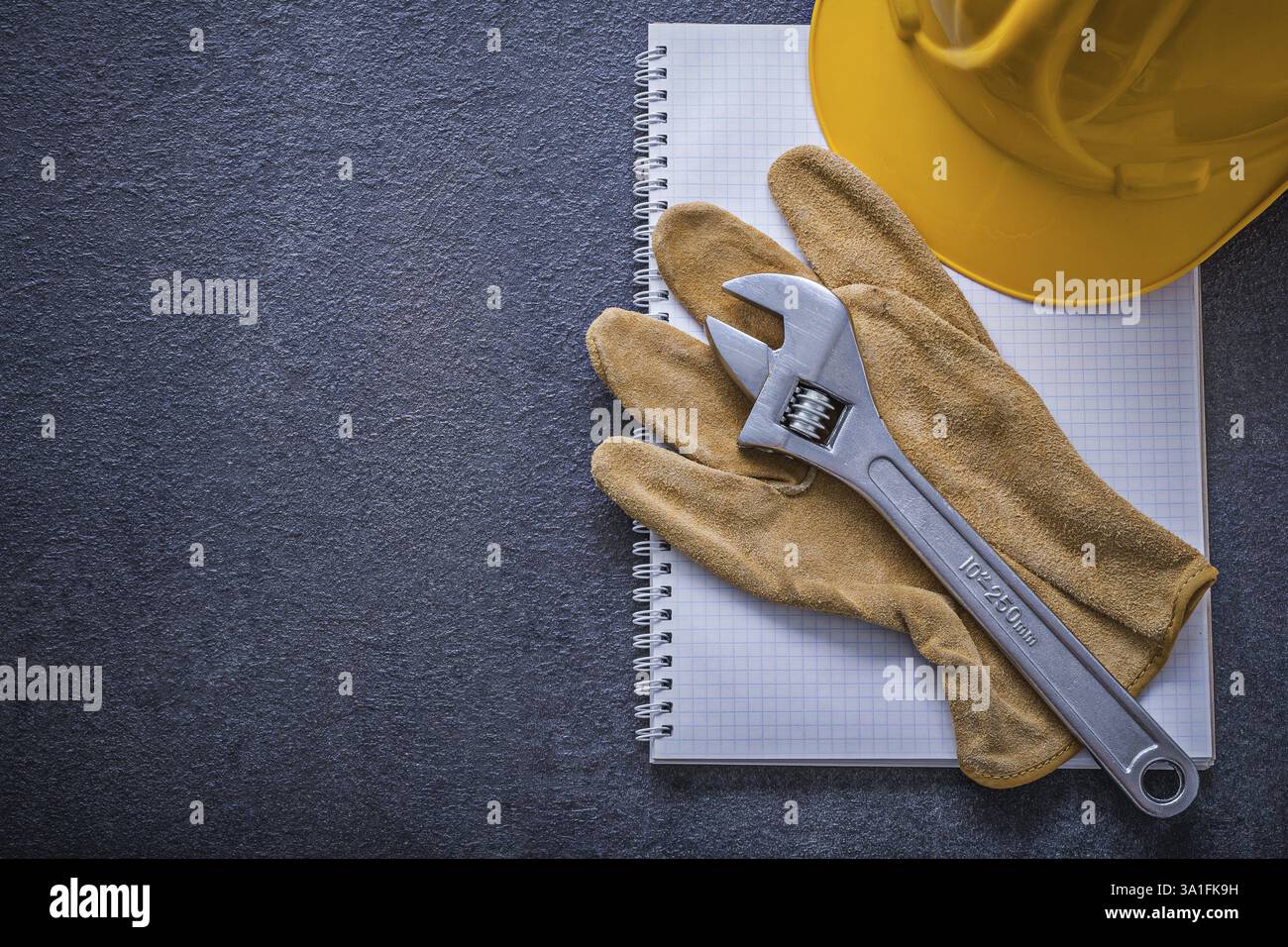Notebook hard hat adjustable wrench protective gloves construction concept Stock Photo