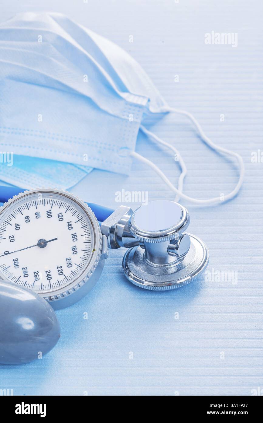 Masks and stethoscope with blood pressure monitor on blue background medical concept Stock Photo