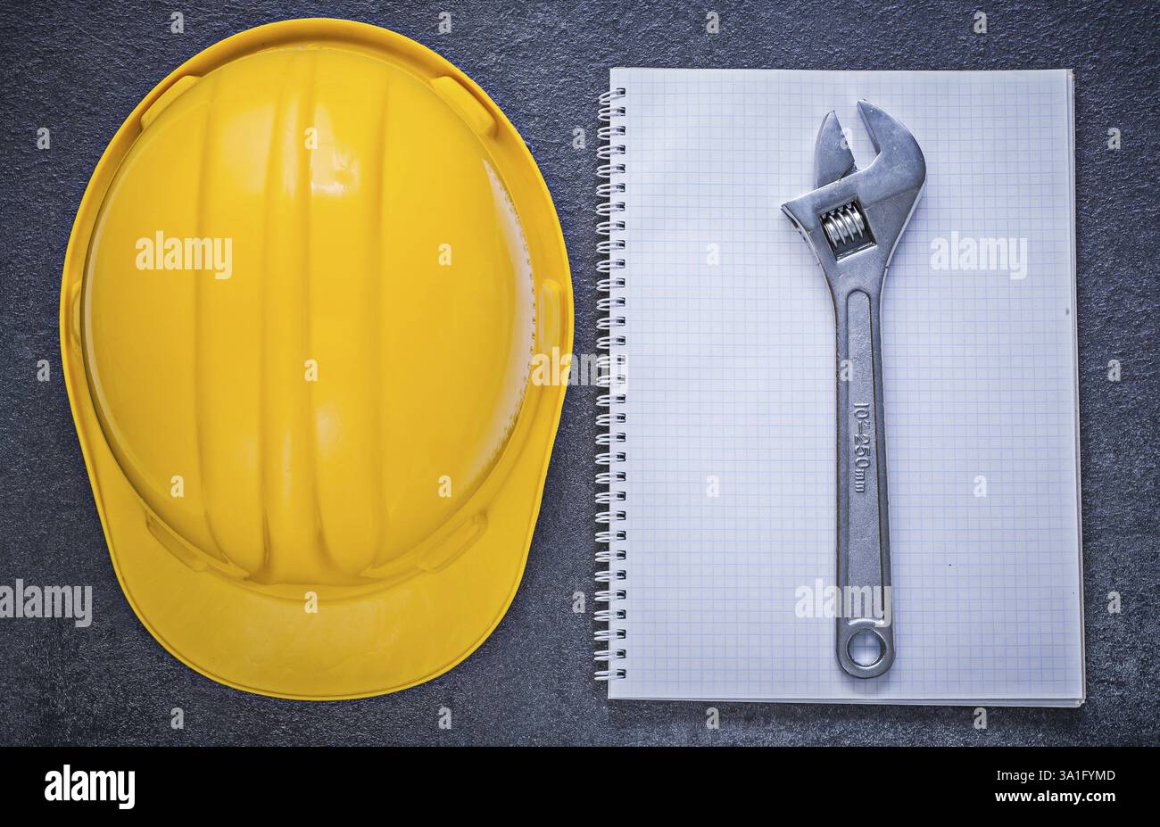 Notebook building helmet adjustable wrench on black background construction concept Stock Photo