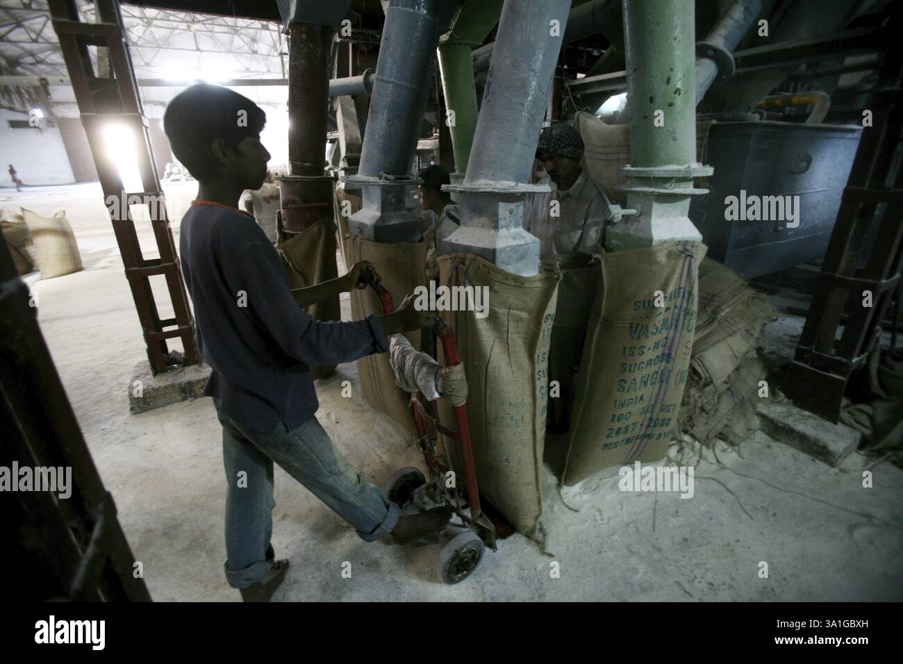 A worker standing with a trolley under the jute bad tied to the mouth ...