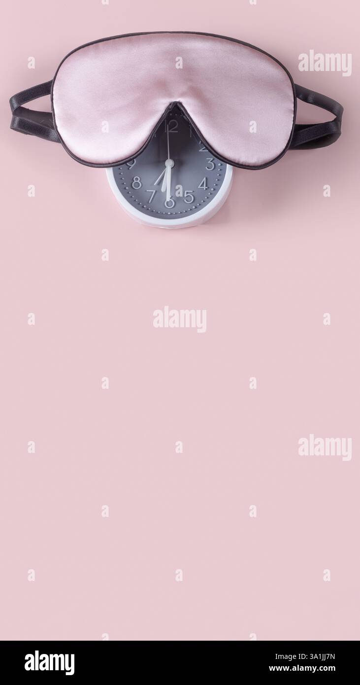 Light pink sleeping mask and alarm clock isolated on pastel pink background. World sleep day concept Stock Photo