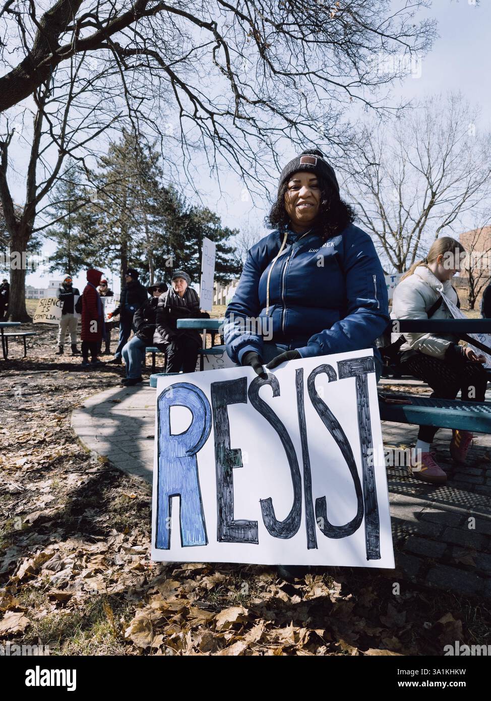 A woman holds a sign reading Resist, at the International Women's Day rally in Flint Michigan USA, March 8 2025 - Smartphone Captured Stock Image