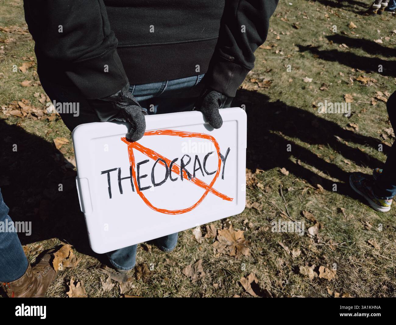 A woman holding a No Theocracy sign at the International Women's Day rally in Flint, Michigan, USA, March 8 2025 - Smartphone Captured Stock Image