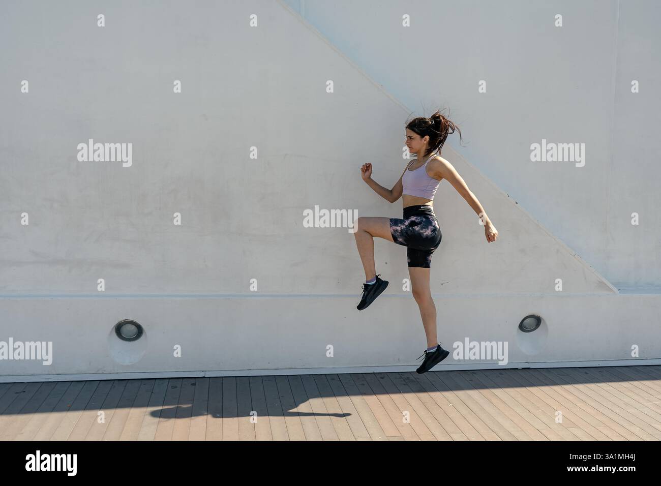 Sporty woman practicing high knees exercise outdoors in urban ...