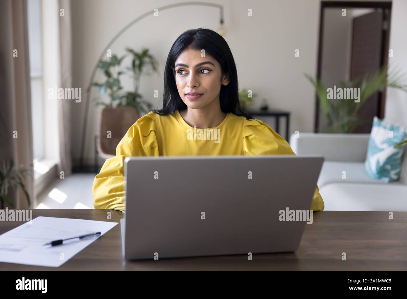 Focused Indian woman working on laptop seated at desk Stock Photo - Alamy