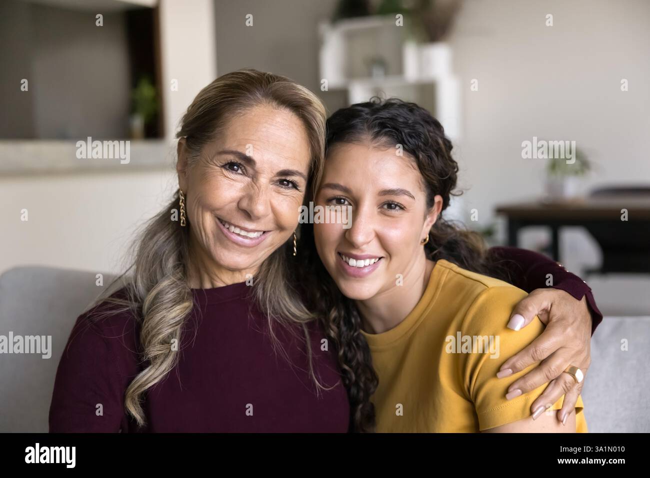 Older Mother Hugging Young Adult Daughter Sitting Together On Sofa older-mother-hugging-young-adult-daughter-sitting-together-on-sofa