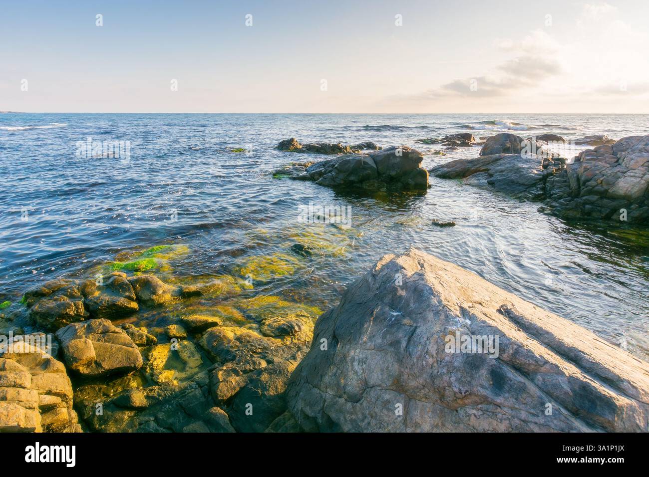 beautiful sunrise at the black sea. scenic seascape. rocky coast and clouds on the blue sky in morning light. summer vacations and weather change conc Stock Photo