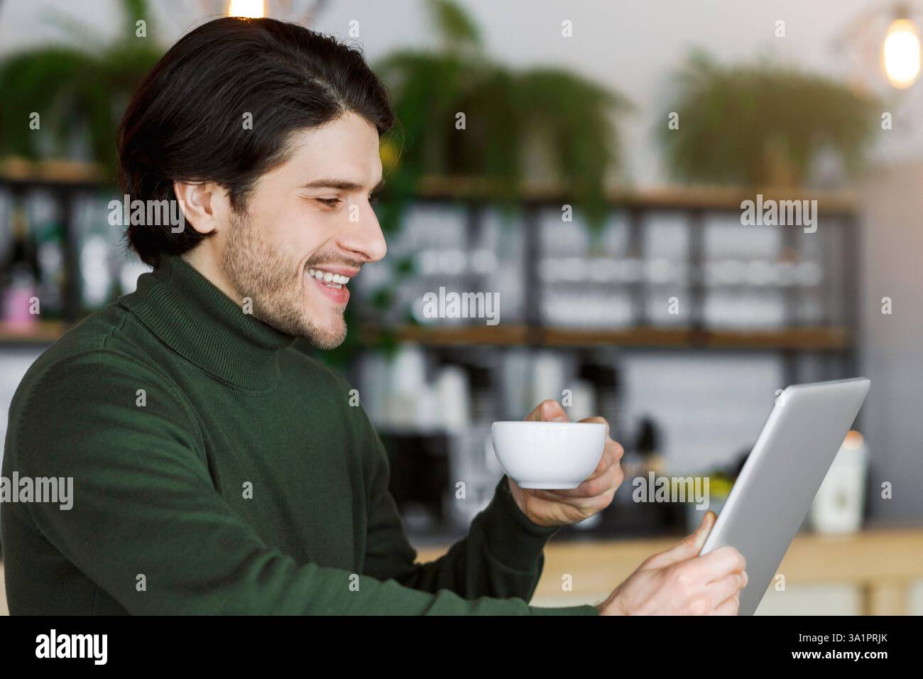 Cheerful man using digital tablet and drinking coffee Stock Photo