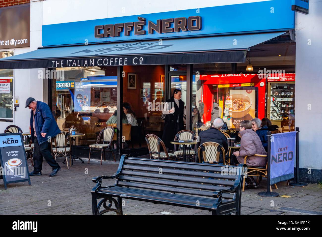 People sit and drink coffee outside of Caffe Nero in Staines-upon-Thames in Surrey, UK. Stock Photo