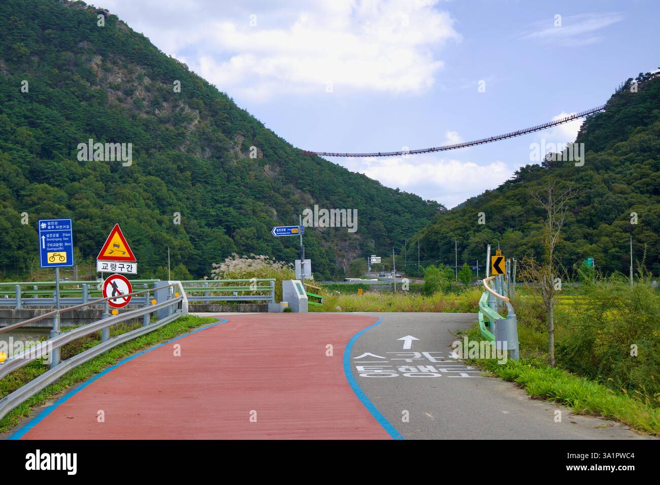 Sunchang County, South Korea - October 4, 2021: A curving cycling path leads toward the towering Chaegye-san Suspension Bridge, which stretches high a Stock Photo