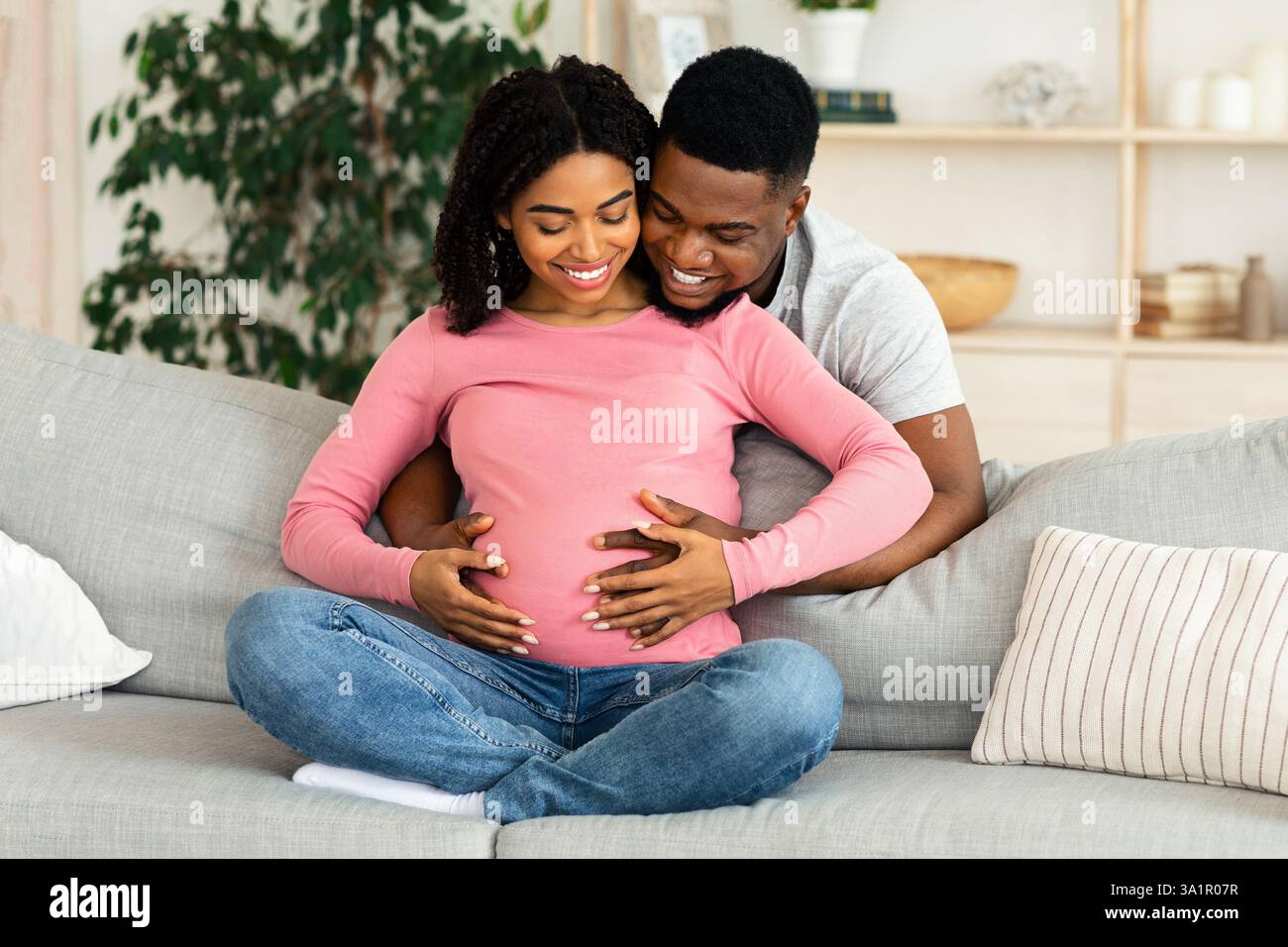 Happy young pregnant african couple cuddling at home Stock Photo - Alamy