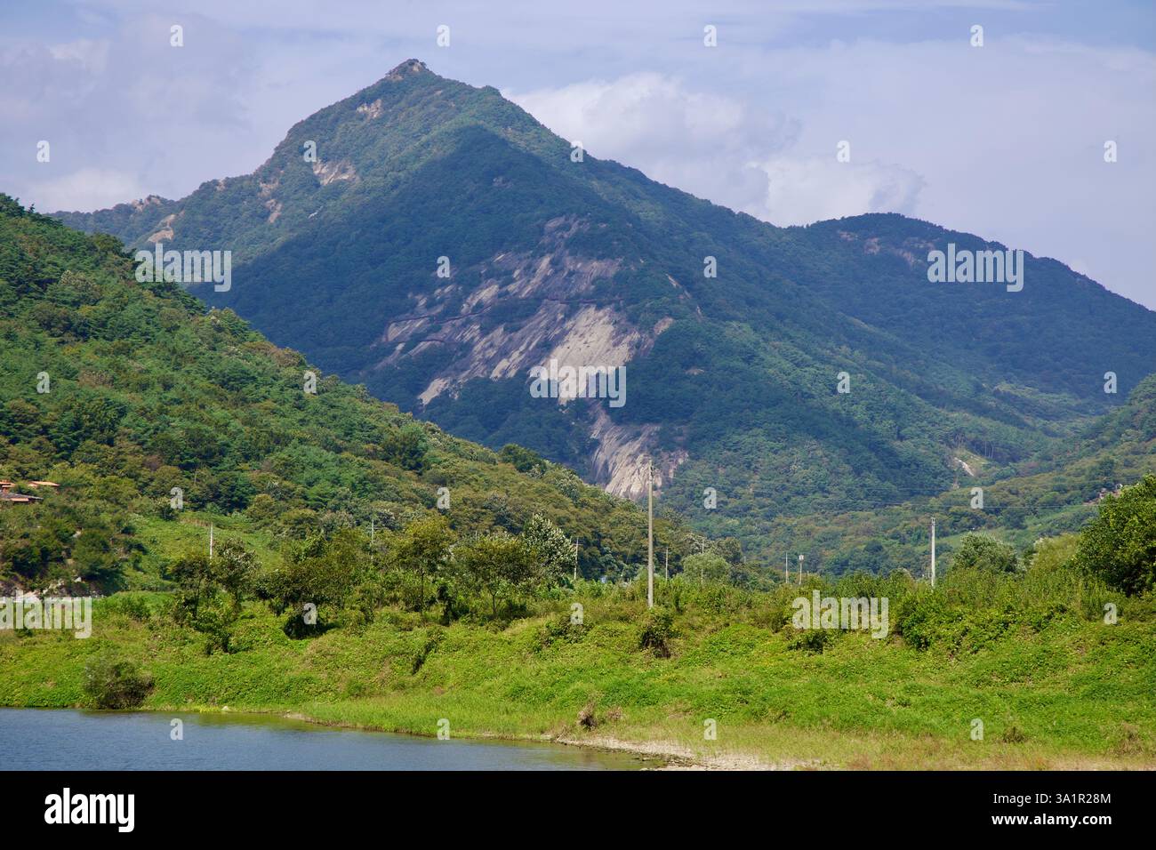 Sunchang County, South Korea - October 4, 2021: A rugged mountain peak rises above the lush greenery along the Seomjin River, with patches of exposed Stock Photo