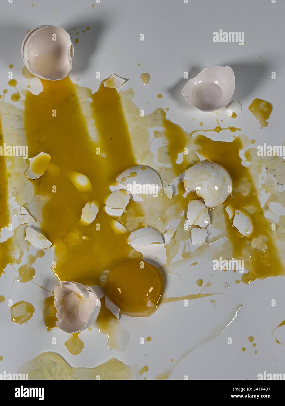 Broken eggs on white background create abstract vertical background plate. Stock Photo