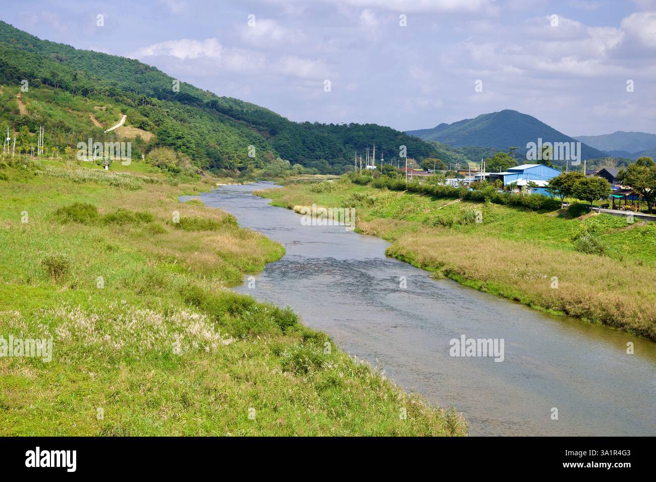Sunchang County, South Korea - October 4, 2021: The Seomjin River winds through lush green fields and rolling hills, with a small rural village in the Stock Photo