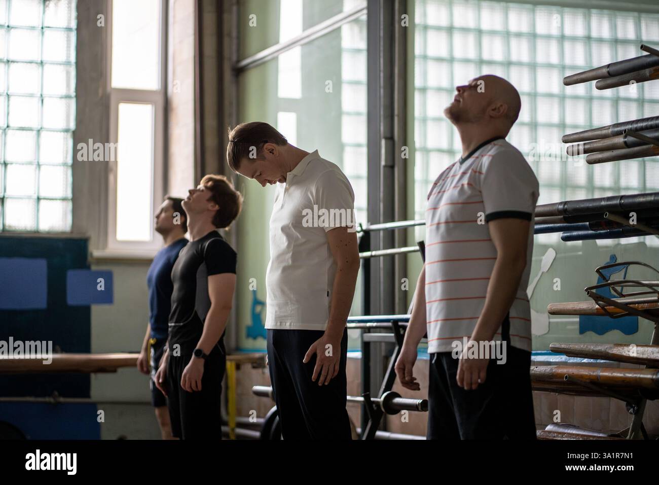 Athletic men warming up dynamic stretching, enhancing flexibility, waving arms before row training Stock Photo