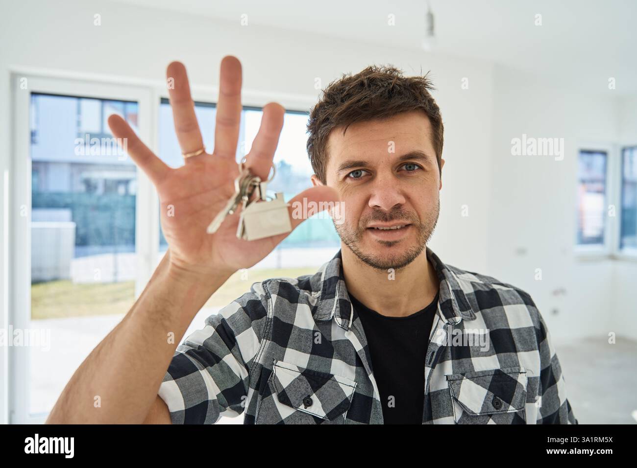 Happy man holding keys to his new apartment. Cheerful male home owner ...