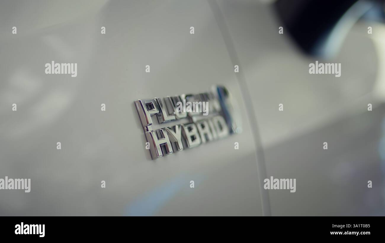 Plug in hybrid electric vehicle equipped with rechargeable battery pack using renewable energy to be emission free. Close up of EV hybrid car logo on eco friendly vehicle Stock Photo